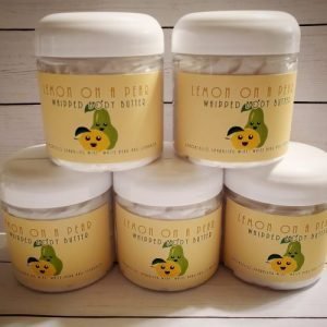 Stack of 5 jars of whipped body butter. The label is yellow with a smiling faced lemon and pear on it. Text above reads "Lemon On A Pear Whipped body Butter"